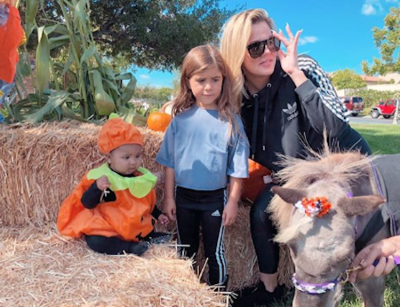 True Thompson wearing a pumpkin costume with Penelope Disick