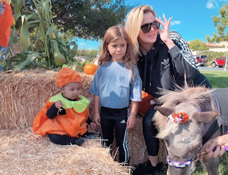 True Thompson wearing a pumpkin costume with Penelope Disick