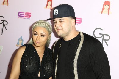 Blac Chyna, wearing black and Rob Kardashian, wearing black and in a hat pose on the red carpet together