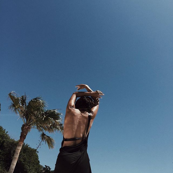 Halle wearing a sports bra with a palm tree in the background
