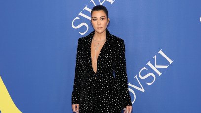 Kourtney Kardashian at an event, wearing an all black low cut outfit