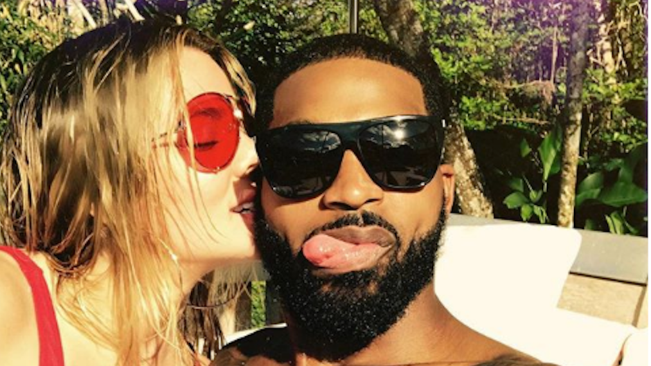 Khloe Kardashian wearing a red bathing suit with Tristan Thompson wearing glasses