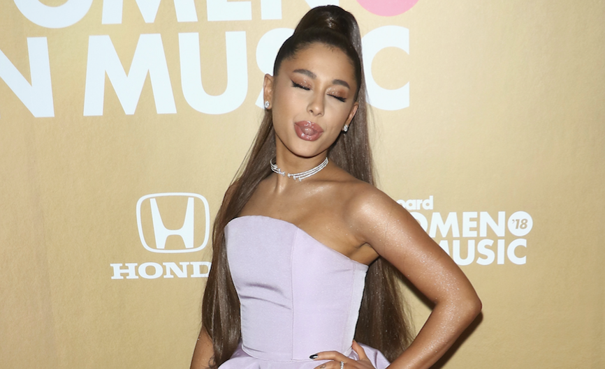 Ariana Grande sticking her tongue out wearing a purple dress