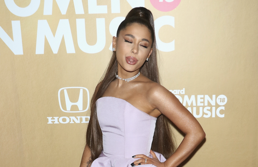 Ariana Grande sticking her tongue out wearing a purple dress