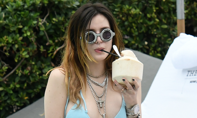 Bella Thorne drinking coconut water while wearing a baby blue bikini