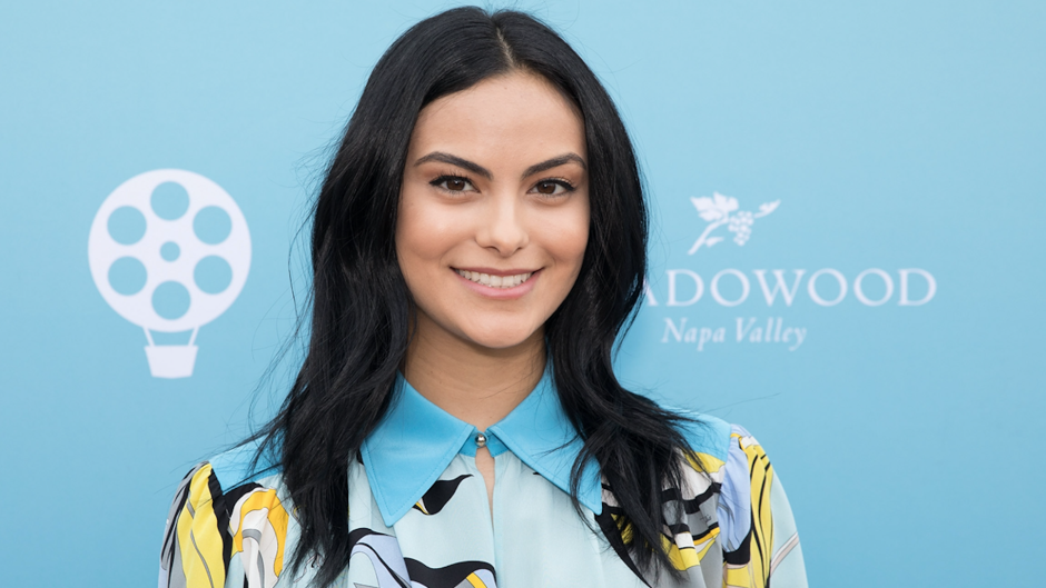 Camila Mendes smiling with her hair down wearing a blue yellow and black dress