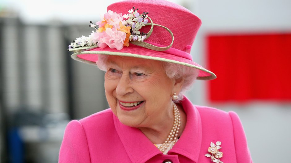 Queen Elizabeth II smiling in a pink outfit and matching hat