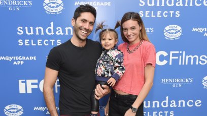 Nev Schulman, wearing all black with daughter and wife, Laura Perlongo, wearing an orange shirt at an event
