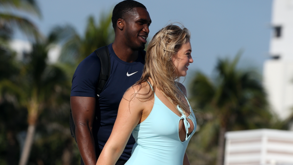 Iskra Lawrence walking with her boyfriend on the beach while wearing a blue bathing suit