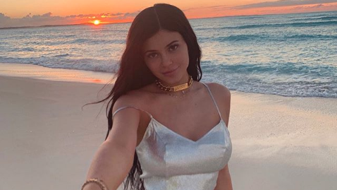 Kylie Jenner on the beach with a sunset in the background