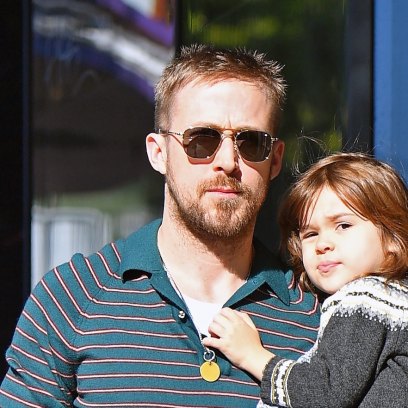 Ryan Gosling wearing sunglasses and carrying his daughter