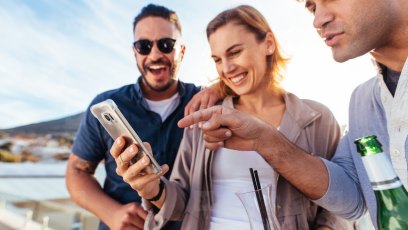 Three people crowded around a cell phone
