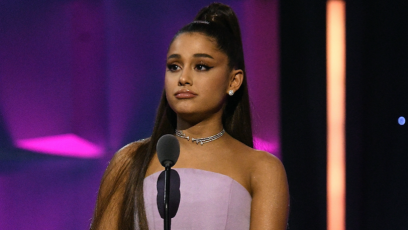 Ariana Grande on stage wearing a purple dress and frowning