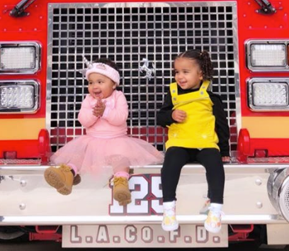 True Thompson and Dream Kardashian sitting on a firetruck