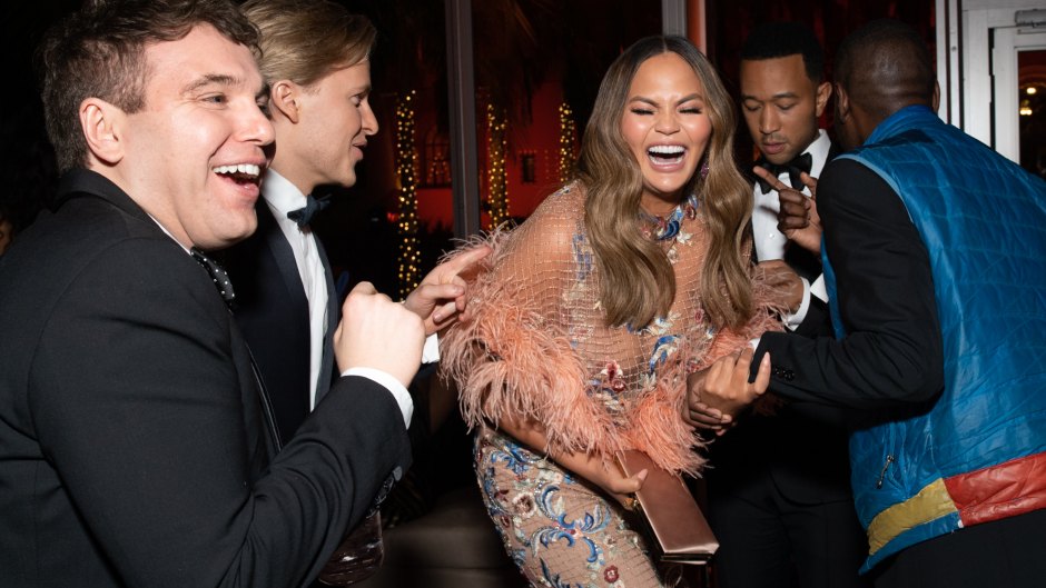 Chrissy Teigen laughing at the oscars wearing a pink dress