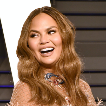 Chrissy Teigen looking over her shoulder and smiling at the 2019 Oscars