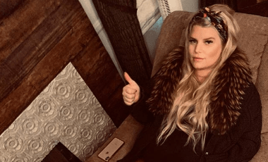 Jessica Simpson pregnant and lounging on a couch giving a thumbs up