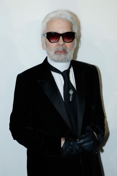 Karl Lagerfeld wearing a black suit, black sunglasses and white ponytail