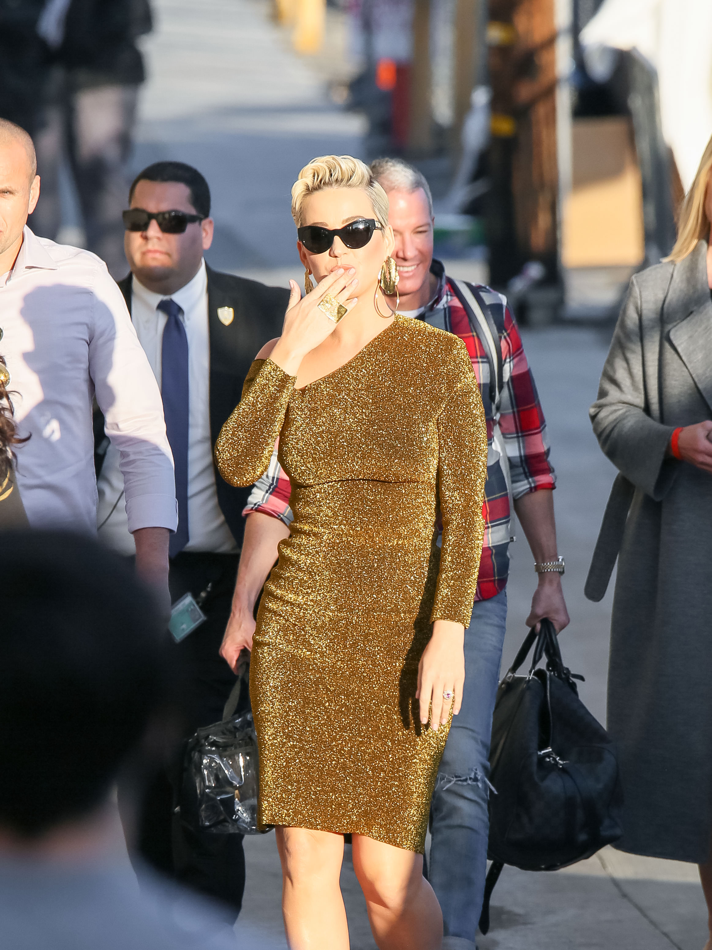 Katy Perry wearing a tight, gold dress with black sunglasses