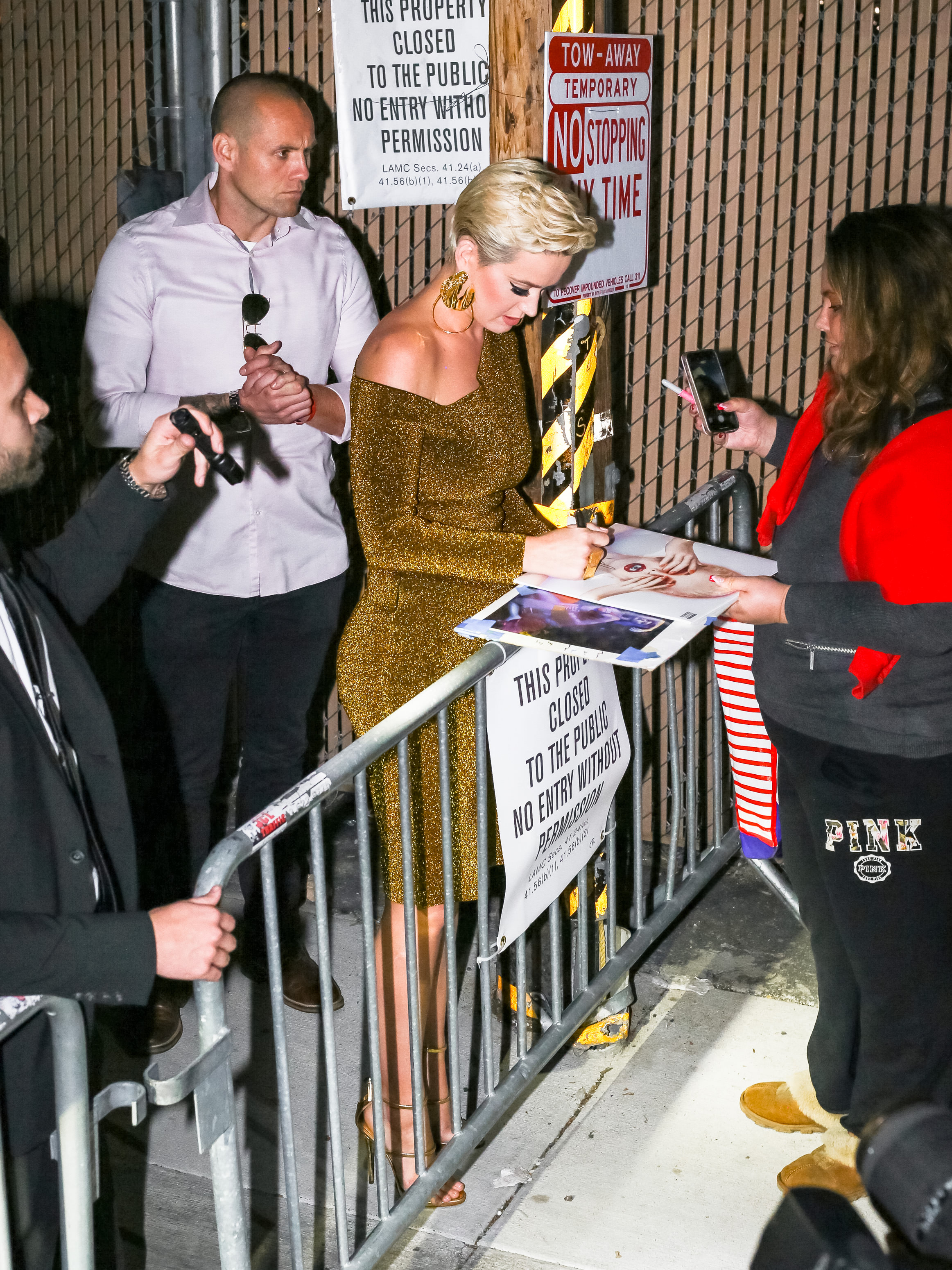 Katy Perry wearing a tight, gold dress with black sunglasses