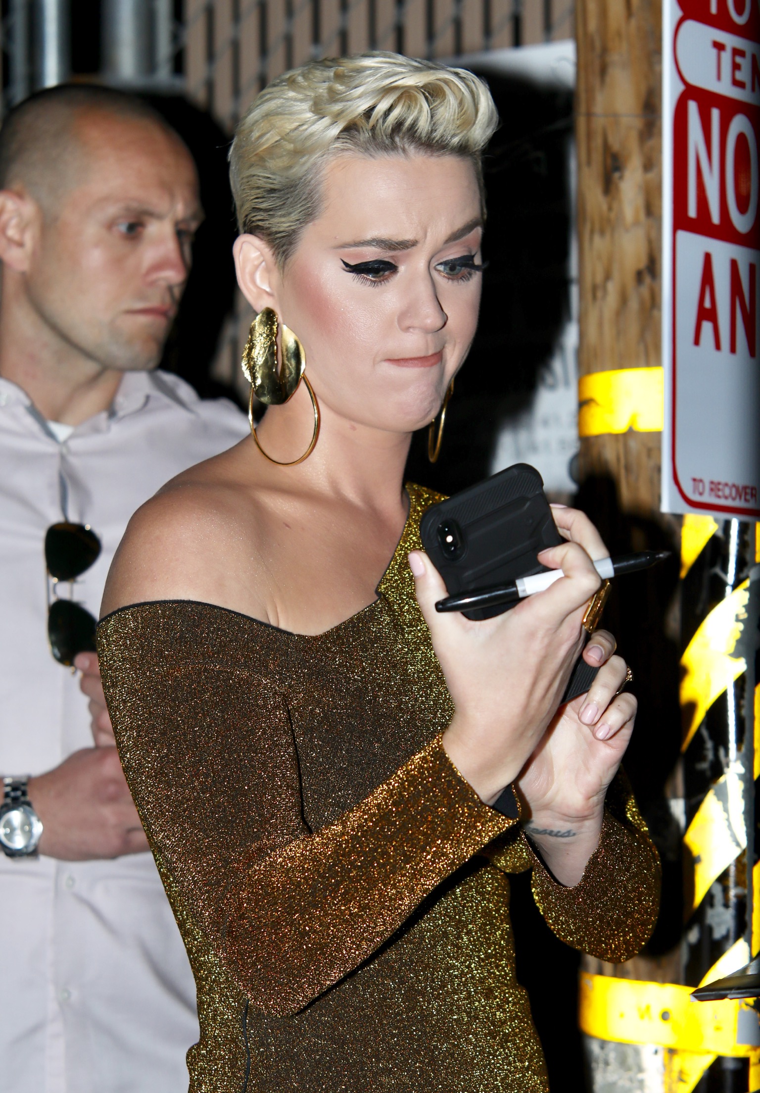Katy Perry wearing a tight, gold dress with black sunglasses