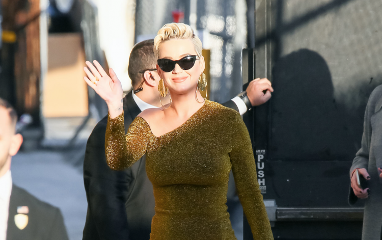 Katy Perry wearing a tight, gold dress with black sunglasses