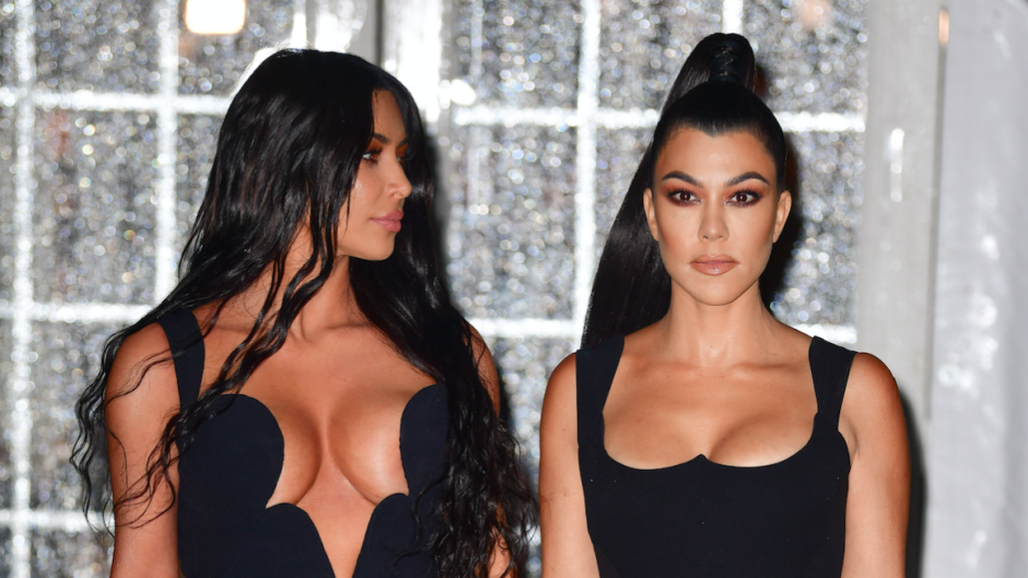 Kim Kardashian looking at Kourtney Kardashian as the pair poses in revealing black dress