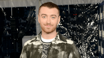 Sam Smith smiling wearing a patterned green jacket