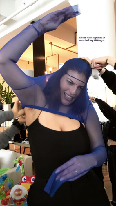 Ashley Graham struggling to fit into a shirt.