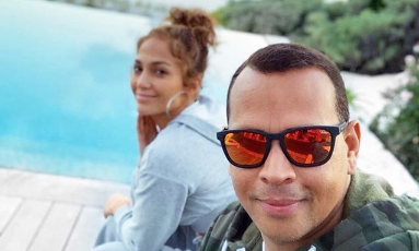 Alex Rodriguez and Jennifer Lopez taking a selfie next to a pool.