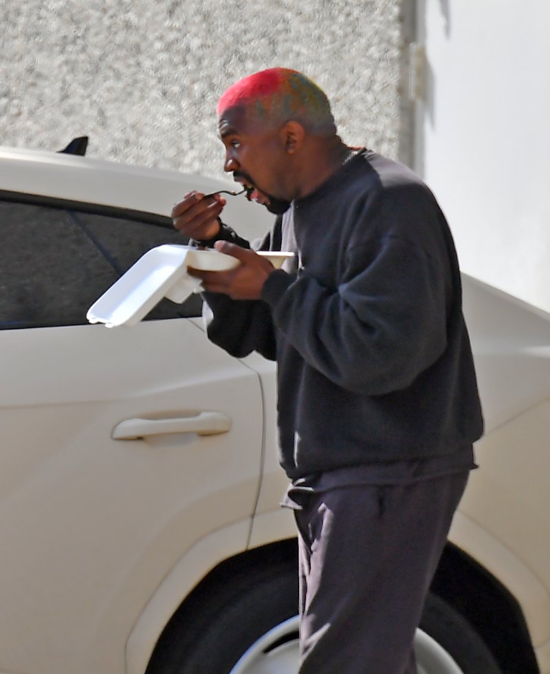 Kanye West walking and eating lunch