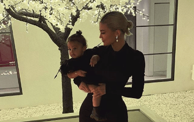 Kylie Jenner holding Stormi Webster while they both wear matching black dresses