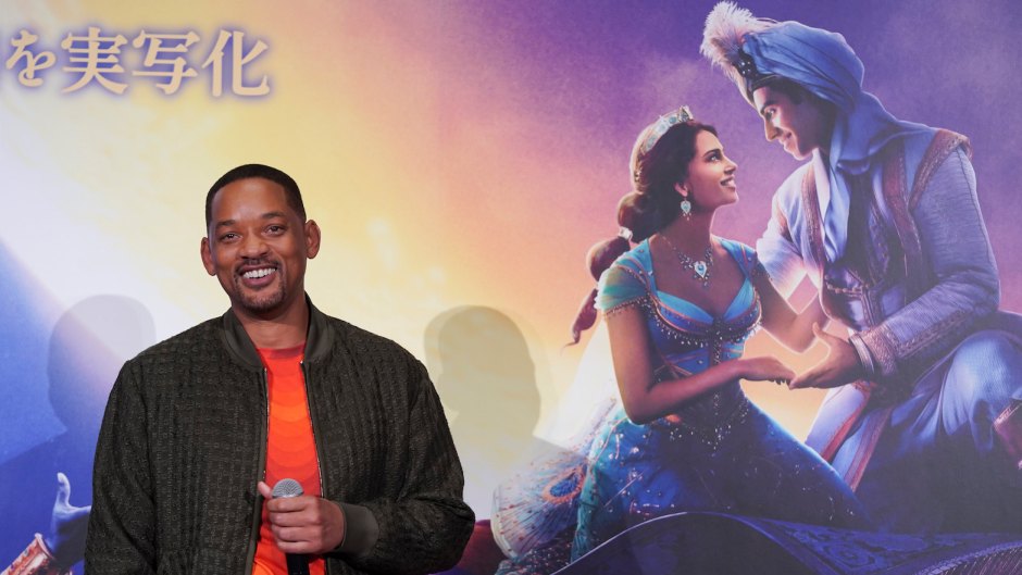 Will Smith Wearing an Orange Shirt In Front of Aladdin Sign