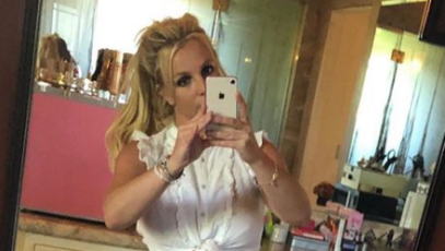 Britney Spears taking a mirror selfie in a white top
