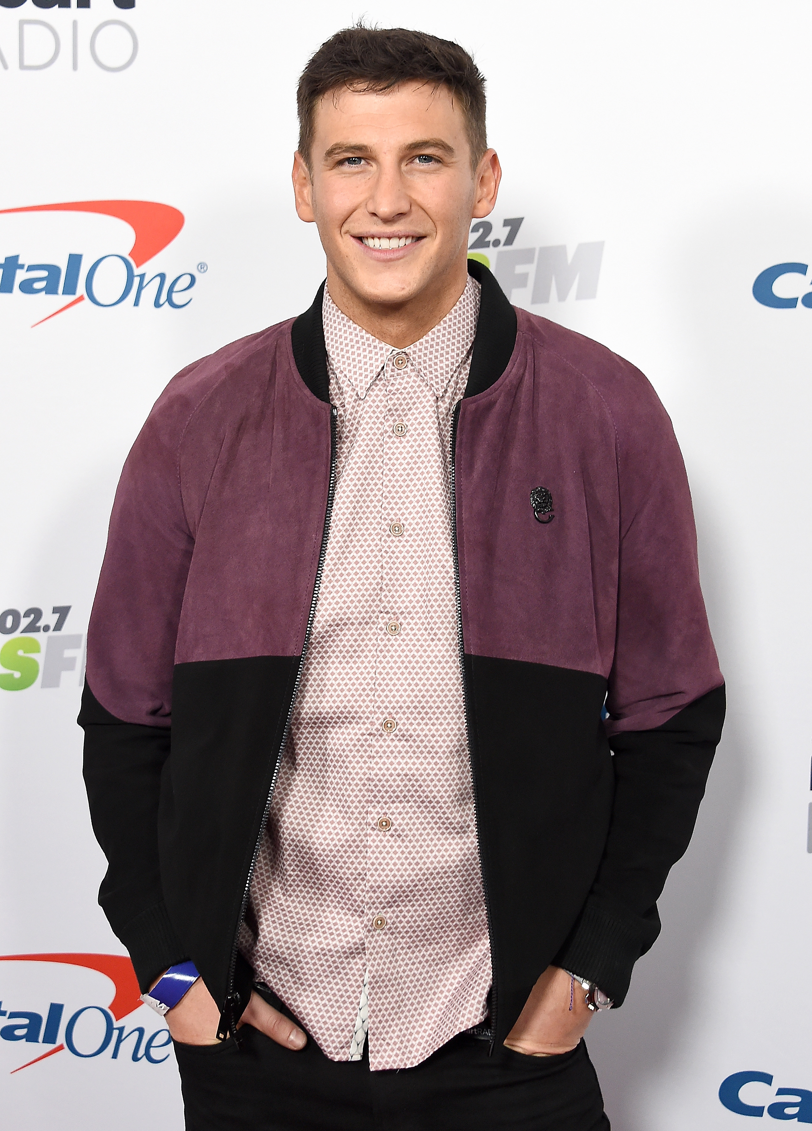 Bachelor Star Blake Horstmann Smiles on Capital One Red Carpet in Pink Button Down Shirt With Purple and Black Bomber Jacket