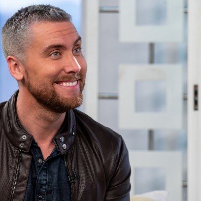 Lance Bass Smiles With Grey Hair and Red Beard in Leather Jacket