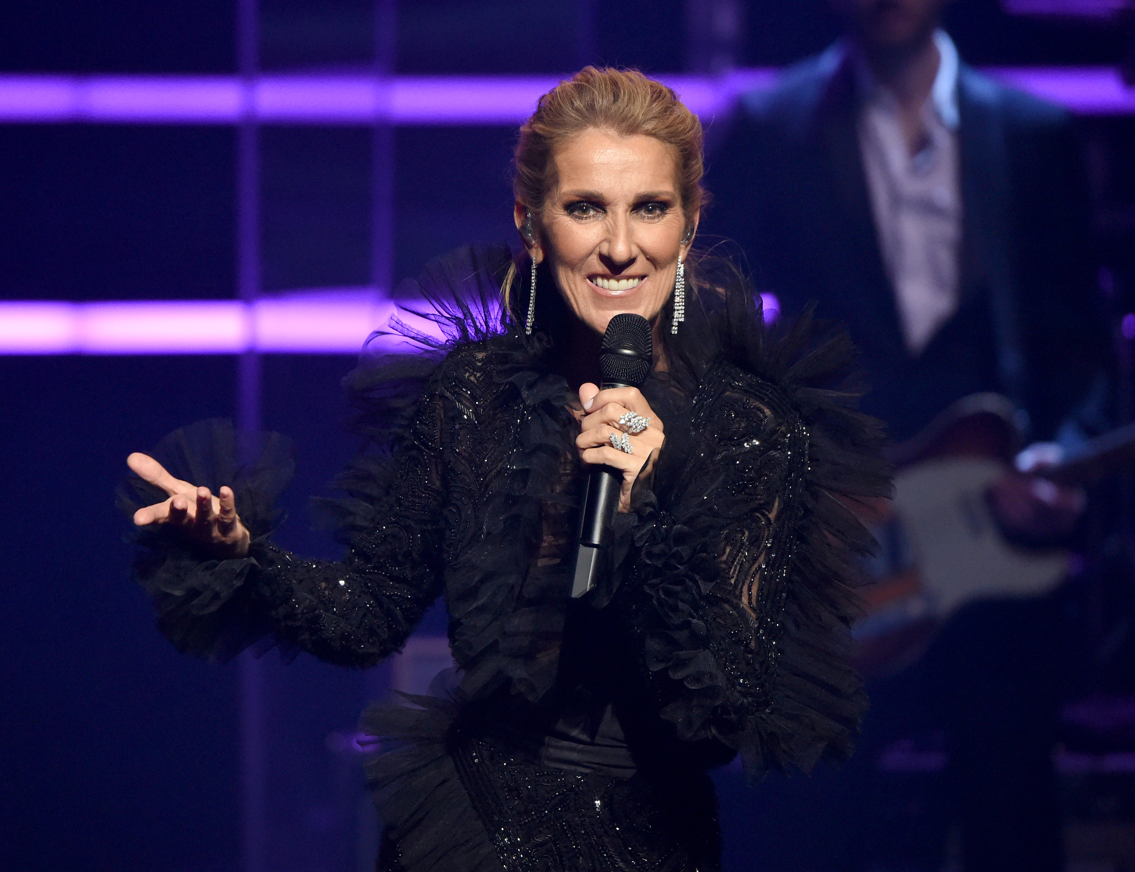 Celine Dion on Stage Holding a Microphone in Black Costume