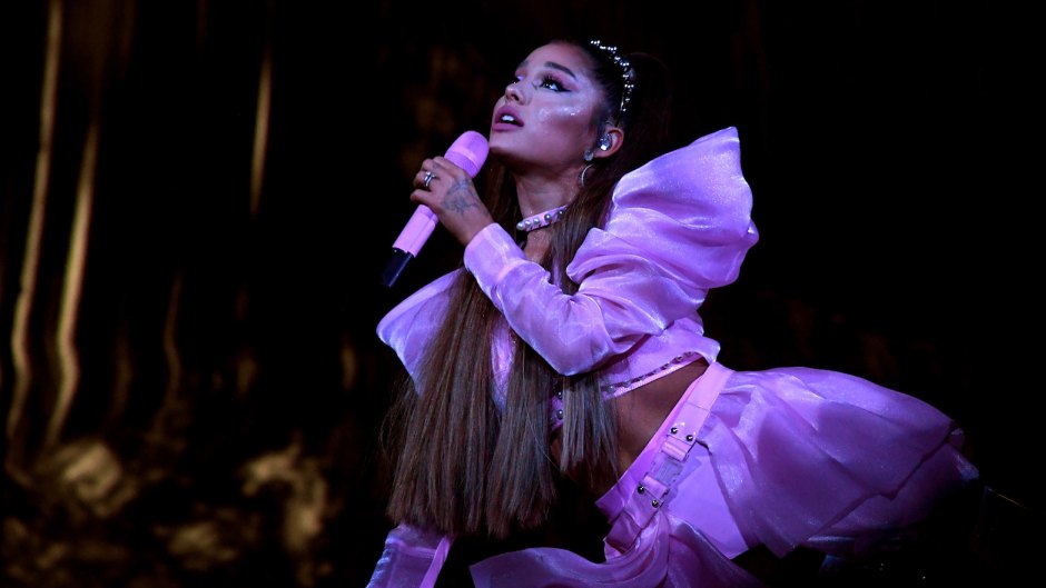 Ariana Grande Lays on Stage During Sweetener World Tour in a Pink Crop Top and Skirt Holding a Pink Microphone