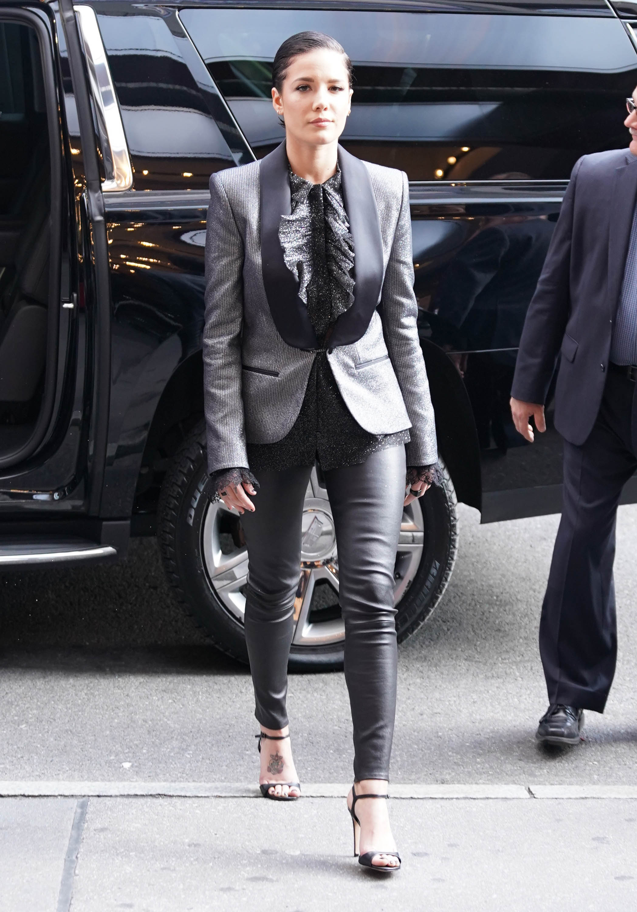 Halsey in a Sparkly Silver Tux Jacket With a Black Blouse and Black Leather Leggings and Short Slicked Back Black Hair