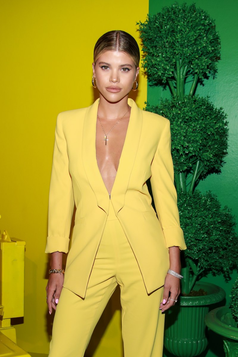 Sofia Richie Poses in a Yellow Suit Jacket With No Shirt and Yellow Pants and Strappy Heels Against a Rainbow Wall