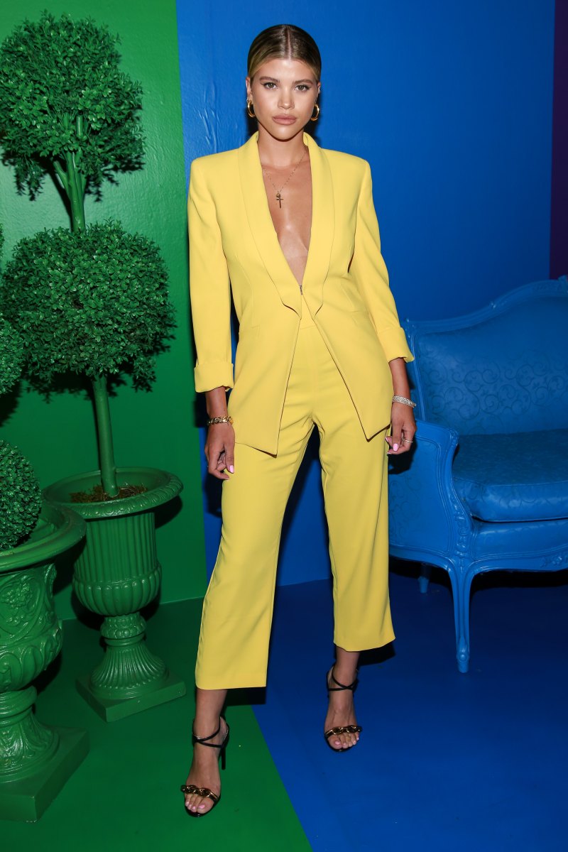 Sofia Richie Poses in a Yellow Suit Jacket With No Shirt and Yellow Pants and Strappy Heels Against a Rainbow Wall