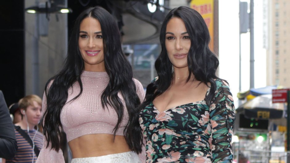 Nikki Bella in a Pink Crop Top and White Lace Pants and Brie Bella in a Flowered Dress Stand Together in New York City