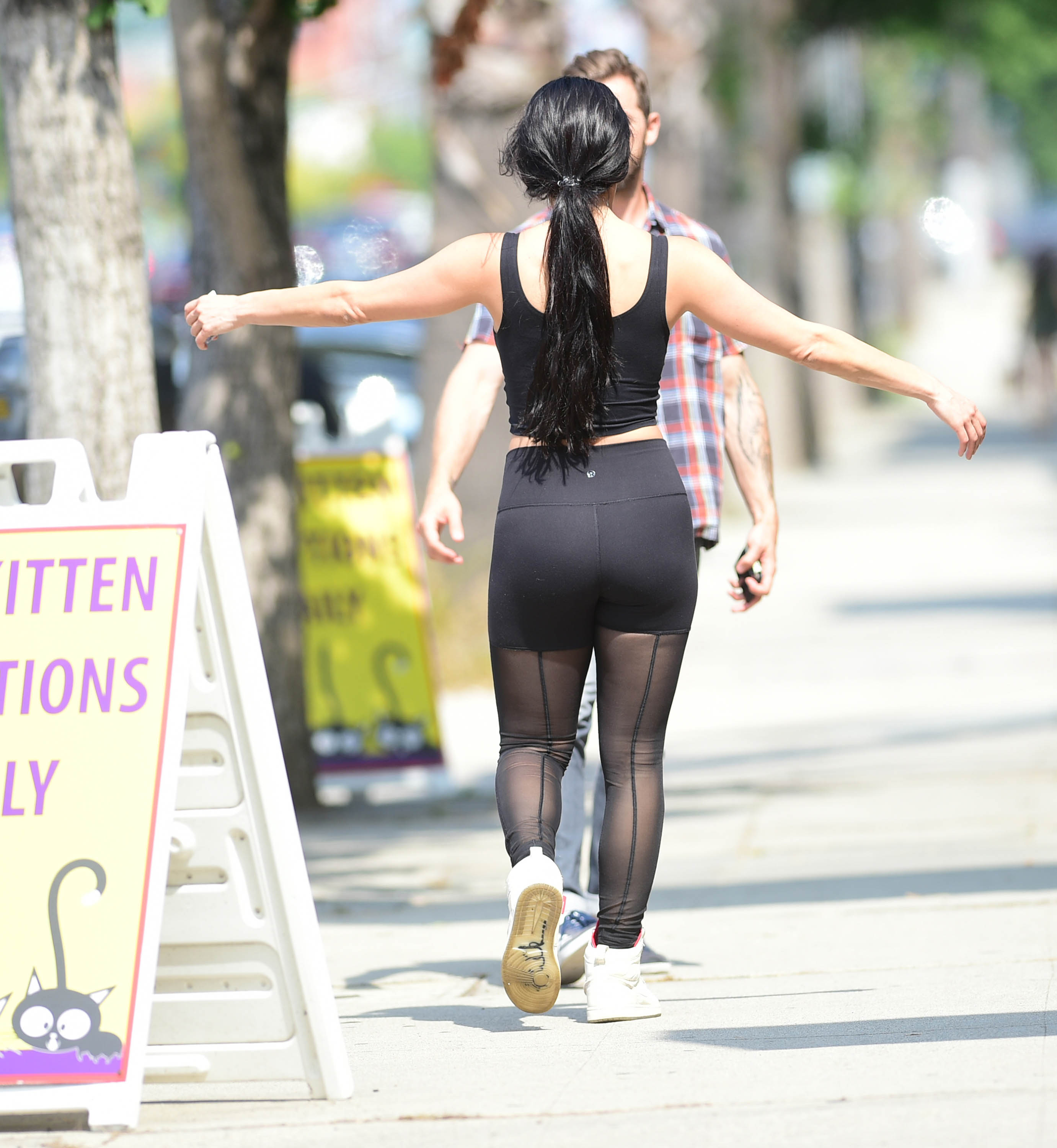 Nikki Bella Wears Black Yoga Pants and Black Sports Bra With Red High Top Sneakers While Hugging Artem Chigvintsev and He Holds Her