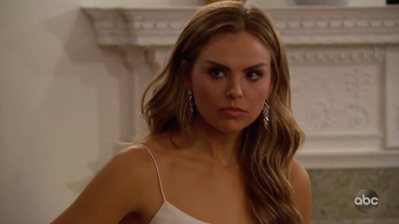 Bachelorette Hannah Brown Stands in White Dress and White Coast With Hair Curled During Week 6 Rose Ceremony