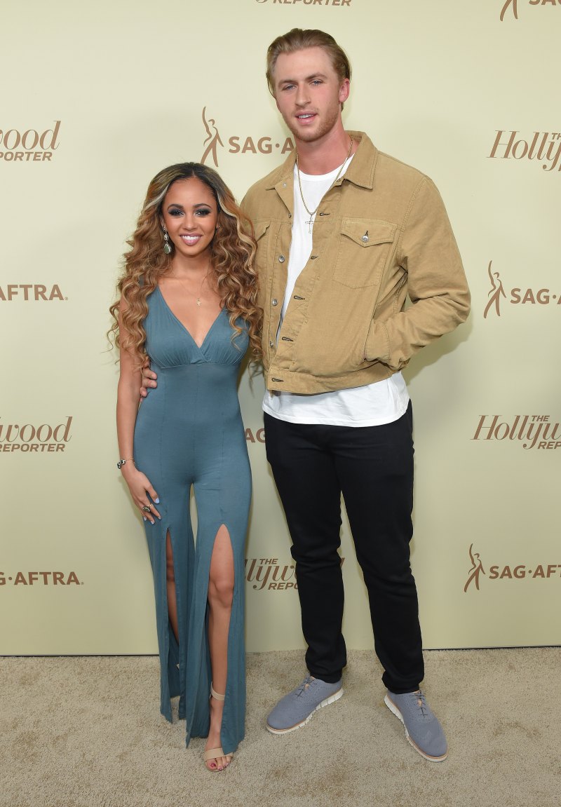 Vanessa Morgan in green dress and curly hair and Michael Kopech in tan jacket and white shirt stand together