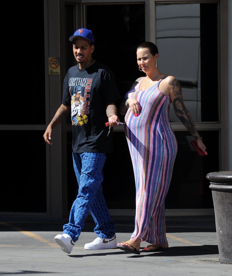 Pregnant Amber Rose cradles her baby bump while wearing a striped summer dress