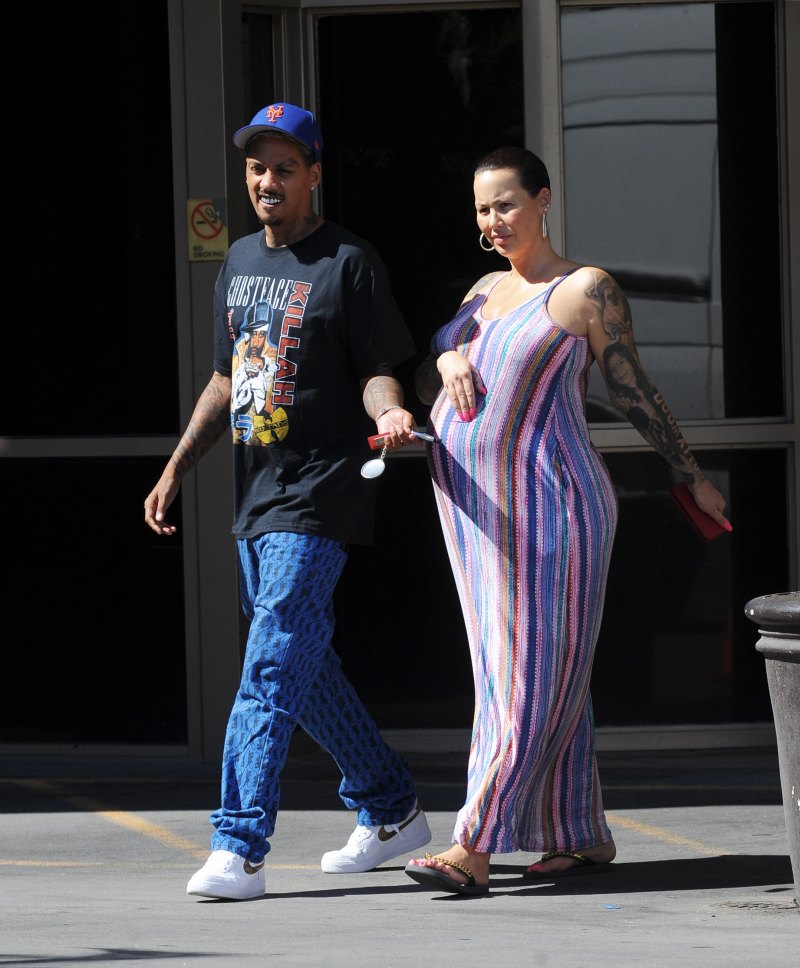 Pregnant Amber Rose cradles her baby bump while wearing a striped summer dress