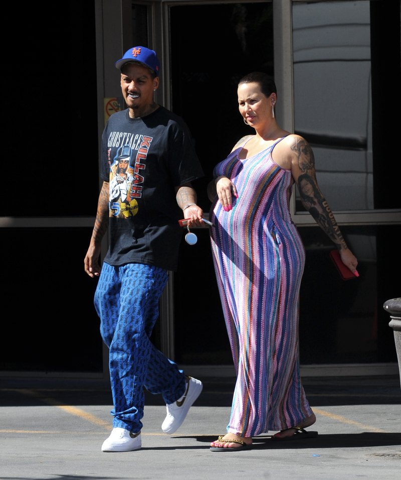 Pregnant Amber Rose cradles her baby bump while wearing a striped summer dress