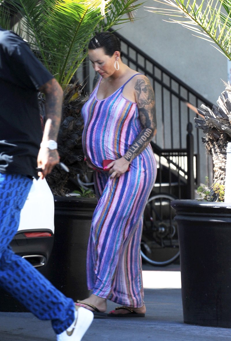 Pregnant Amber Rose cradles her baby bump while wearing a striped summer dress