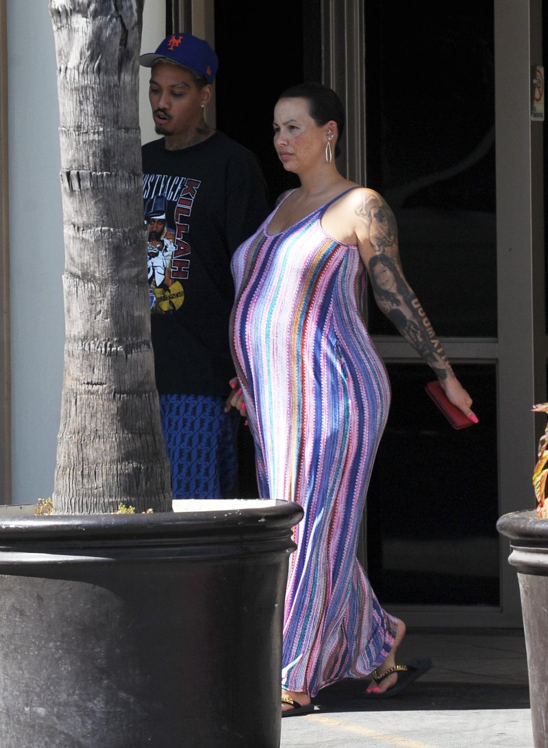 Pregnant Amber Rose cradles her baby bump while wearing a striped summer dress